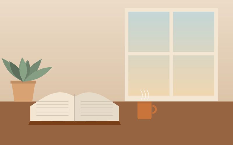 كتابٌ مفتوح وكوبٌ عند نافذة