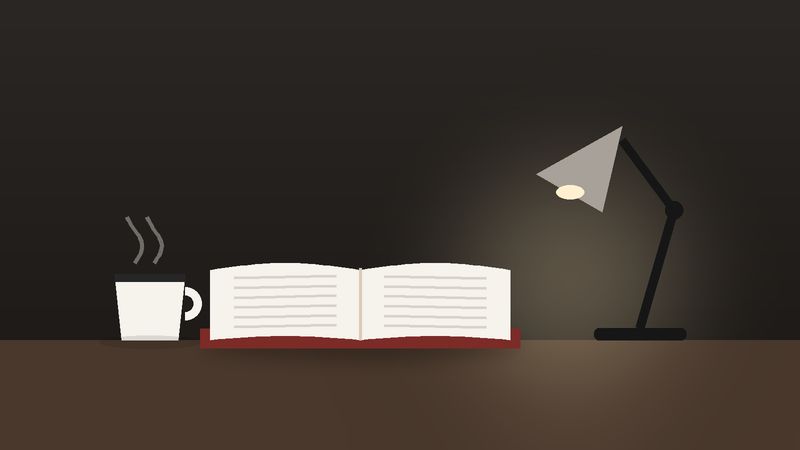 كتابٌ مفتوح وكوبٌ تحت ضوء مصباح