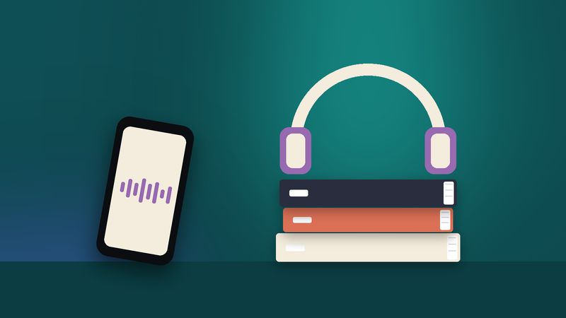 سمّاعتان فوق كتبٍ مكدّسة وهاتفٌ بجانبها
