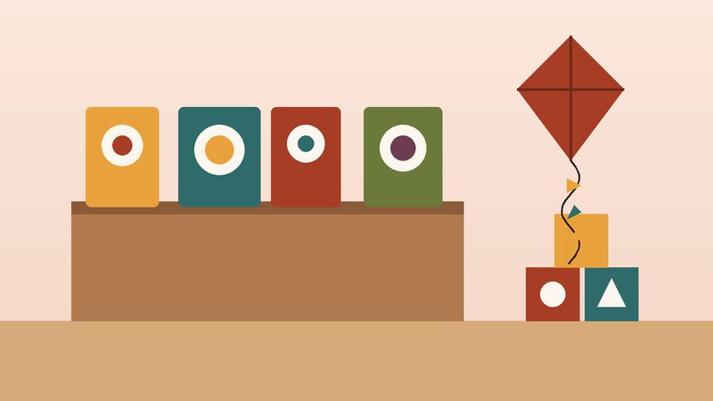 كتبٌ مصوّرة على رفٍّ منخفض ومكعّباتٌ وطائرةٌ ورقيّة